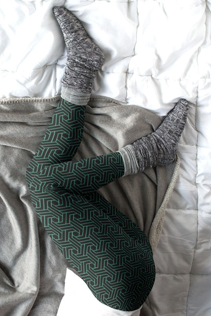 These custom handmade women's high waisted leggings are black in color with a glowing green geometric pattern overlayed on the top.