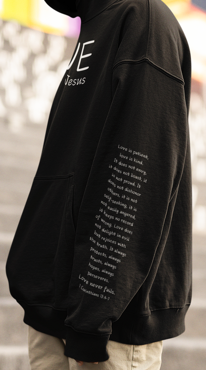 A cozy and warm custom Christian hoodie featuring a powerful message of love and faith. The front displays the word LOVE Like Jesus, accompanied by a cross with a heart. Each sleeve showcases the scripture 1 Corinthians 13:4-7