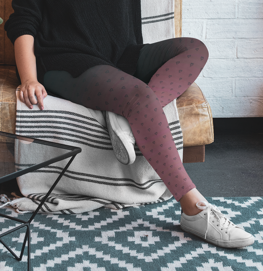 A pair of women's custom high waisted leggings that start as black at the top then fade to a light pink at the bottom, there are hearts all over the leggings then they fade into the black at the top of the pant.