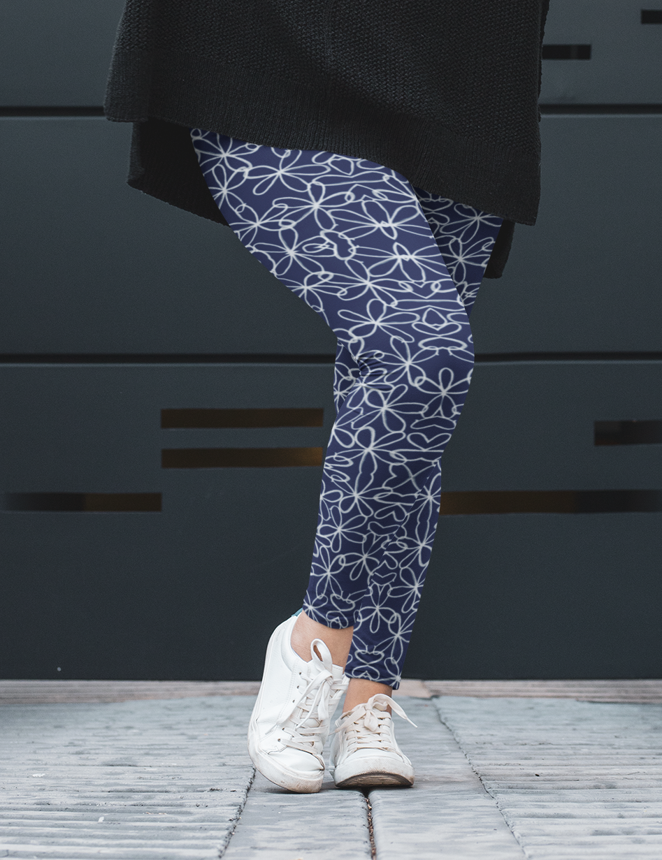 A pair of navy blue women's high waisted leggings with a white floral pattern all over the handmade pants.
