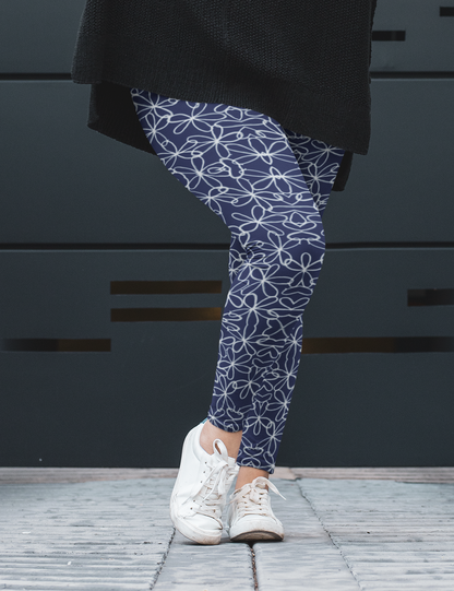 A pair of navy blue women's high waisted leggings with a white floral pattern all over the handmade pants.