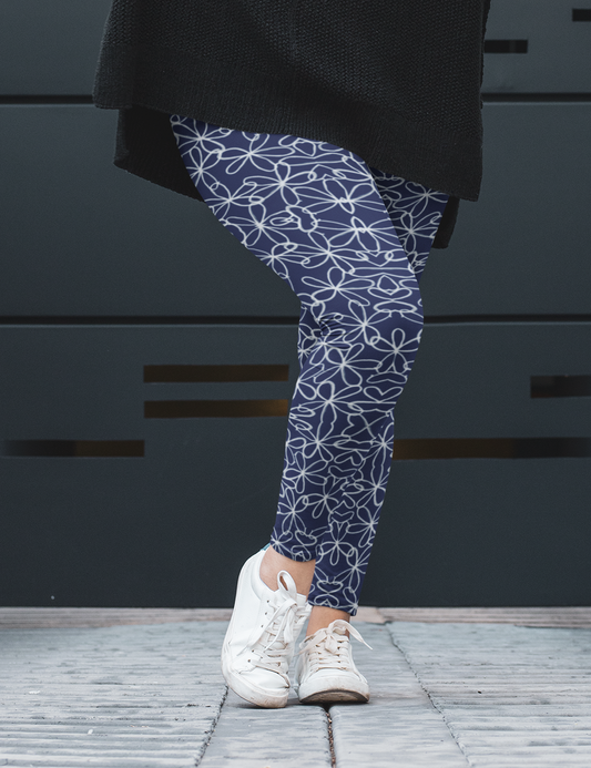 A pair of navy blue women's high waisted leggings with a white floral pattern all over the handmade pants.