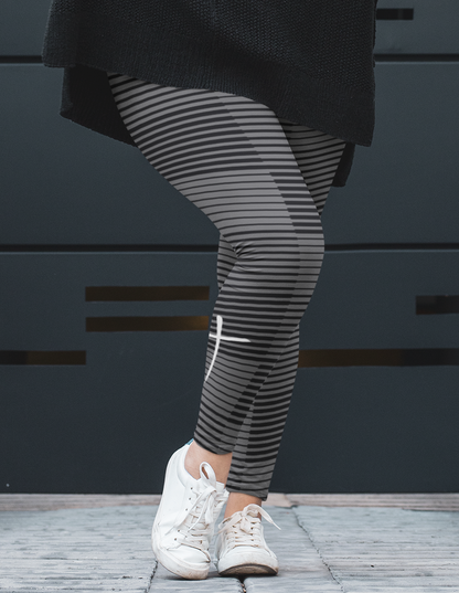 A pair of women's high waisted Christian themed leggings, the pants are light grey  color with black stripes running across the pants, the lines are in different thicknesses from the top to the bottom ankle of the leggings giving it a 3D look when worn, there is a white Jesus cross on the bottom right calf of the pant.