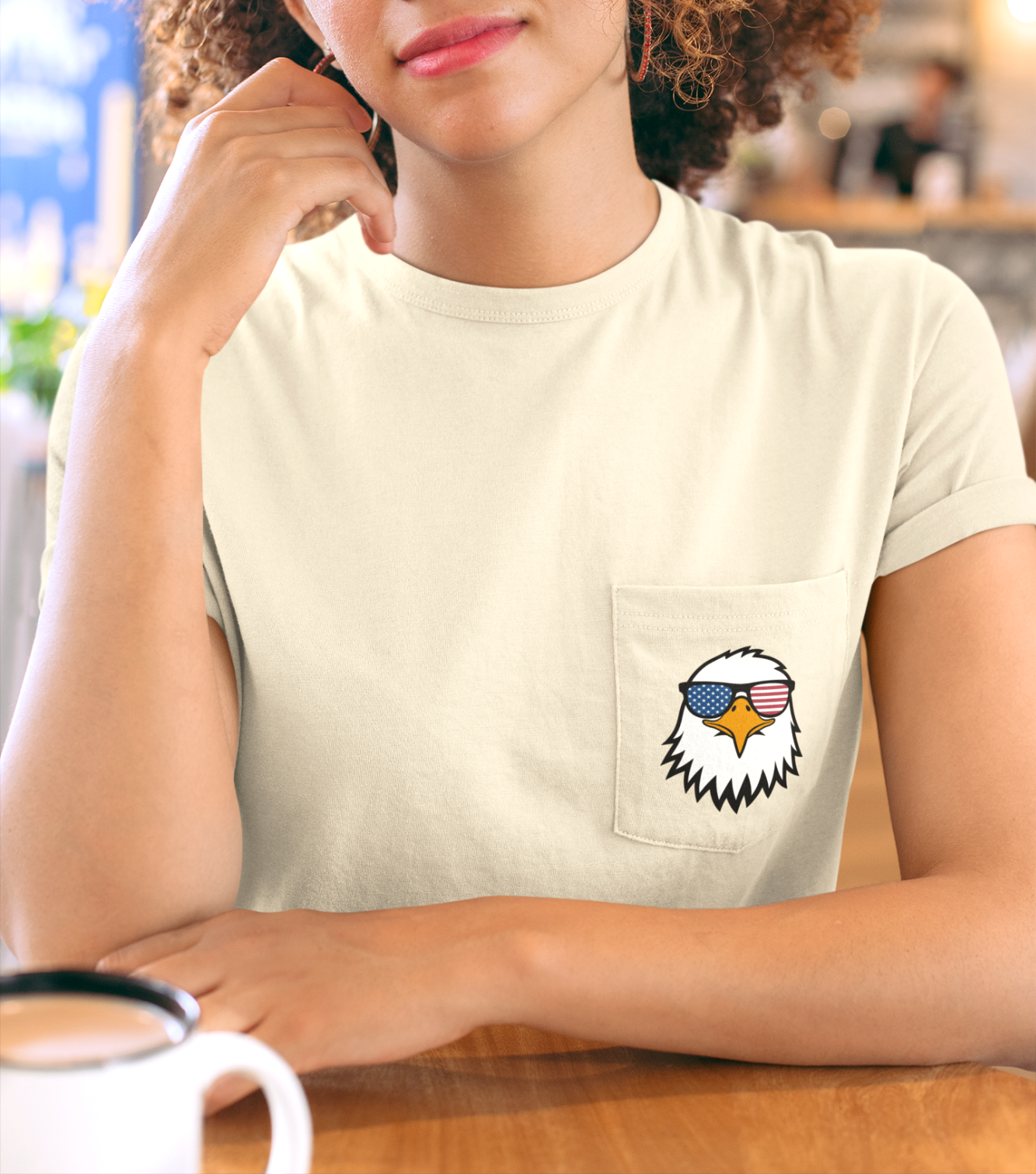 On the front of this custom t-shirt is a image of a bald eagle wearing a pair of sunglasses that have the American flag in the lenses.