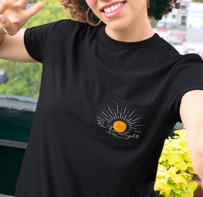 A custom Christian unisex pocket t-shirt, on the pocket that is over the left chest of the shirt is a large sun with the words Be The Light Matthew 5:14 of the Bible.