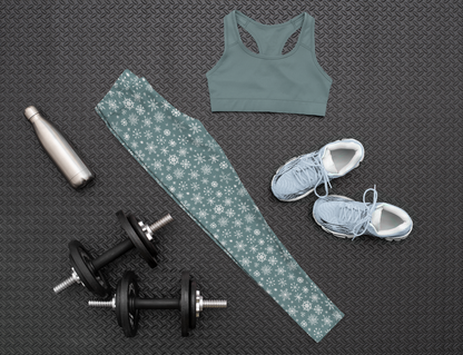 A pair of high waisted custom women's leggings that are a light blue in color and have white snowflakes all over the pants, perfect for Christmas.