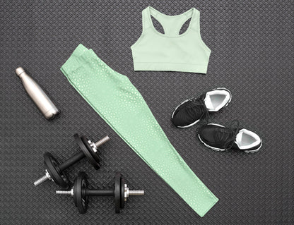 These high waisted women's leggings are a light green with a geometric pattern overlayed overtop, some spots are brighter than others showcasing some spots more than others.