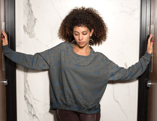 This custom women's all over print sweater has a silver to black ombre pattern starting at the neckline then fading to black at the bottom. There is a blue floral pattern overlayed on the top, perfect for anyone looking to stand out.