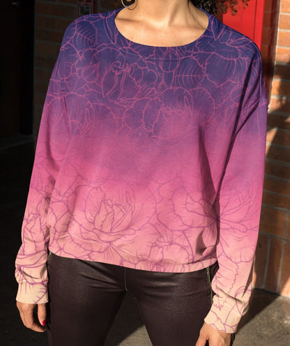 The sweater has a washed ombre pattern starting as a dark purple at the top of the neckline then fading to a light purple then to a bright pink then to a blush pink at the bottom, there is a purple floral pattern imposed on the top of the sweater.