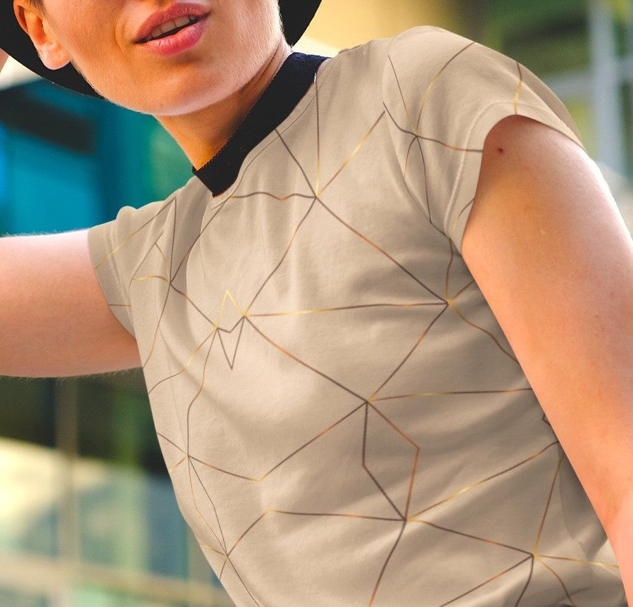 This custom women's handmade short sleeve shirt is a light beige color with with gold lines all over the shirt in a geometric pattern, some spots of the gold lines are brighter than others making it seem like the gold lines are glowing.