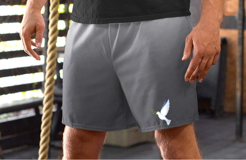 These custom men's board shorts feature a unique design with a ombre pattern starting with a light grey at the top then fading to a dark grey at the bottom, there is a symbol of a dove carrying a fig leaf on the front left side of the shorts just at the knee.