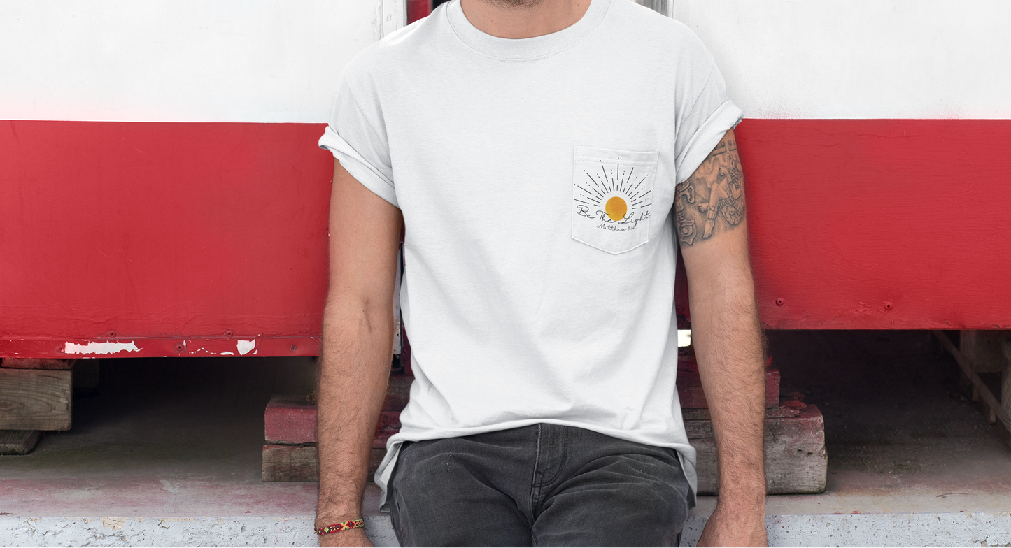 A custom Christian unisex pocket t-shirt, on the pocket that is over the left chest of the shirt is a large sun with the words Be The Light Matthew 5:14 of the Bible.