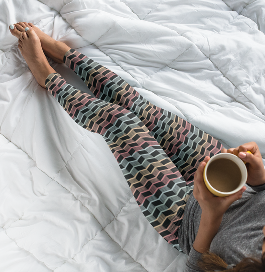 Custom women's leggings with rows of pastel red, yellow and blue from the top to the bottom of the leggings, there is a black abstract pattern overtop of the colors giving the leggings a 3D look.